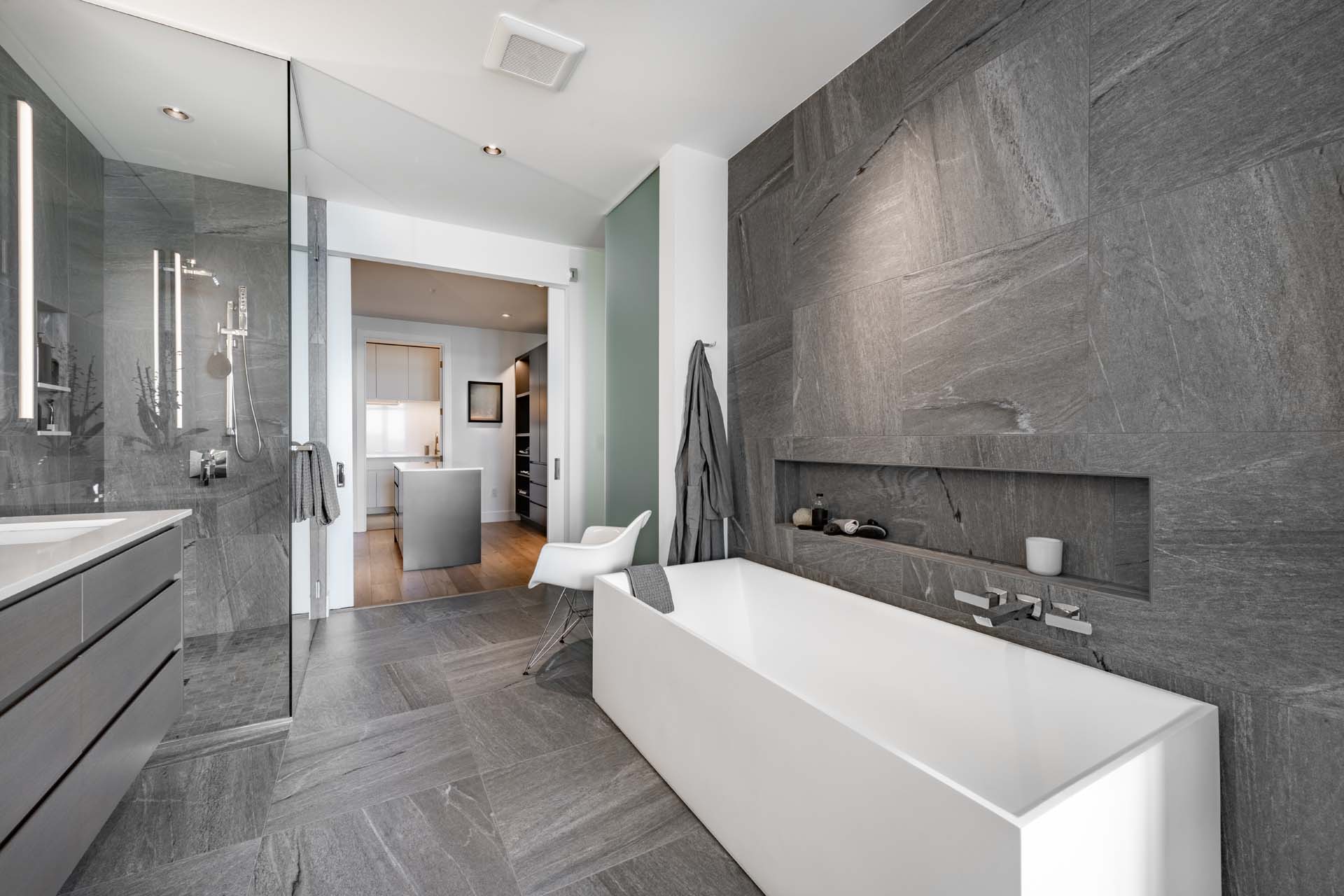 Contemporary condominium in pacific northwest grey cabinets masculine style primary bathroom walk in wardrobe closet laundry room powder room lavatory slate dark colors white sink toilet bathtub robe