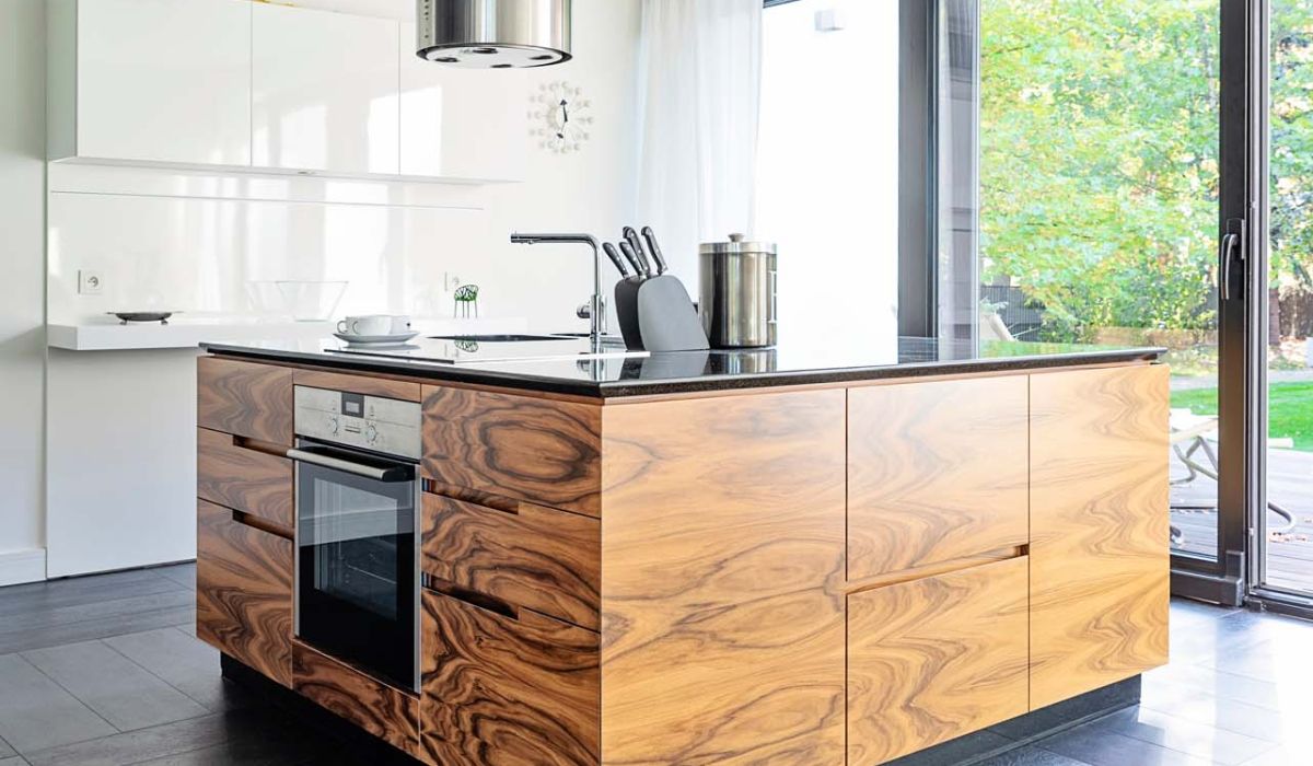 Modern kitchen interior with wooden kitchen island with oven and window in the room. Design indoors architecture and luxury in new apartment with tiled floor. Vertical.